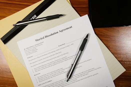 Flat lay of a marital dissolution agreement form with pens and files on a desk.